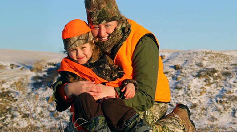 Close up of Mother with her child in the wilderness wearing blaze orange camouflage